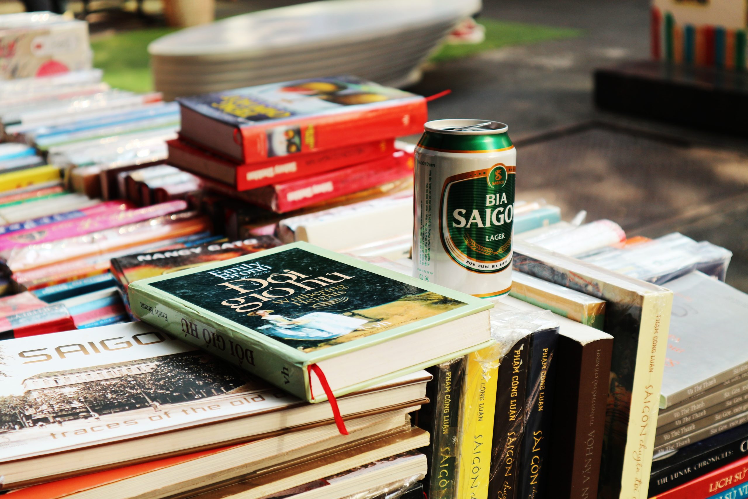 A stack of books sits with a can of Bia Saigon.